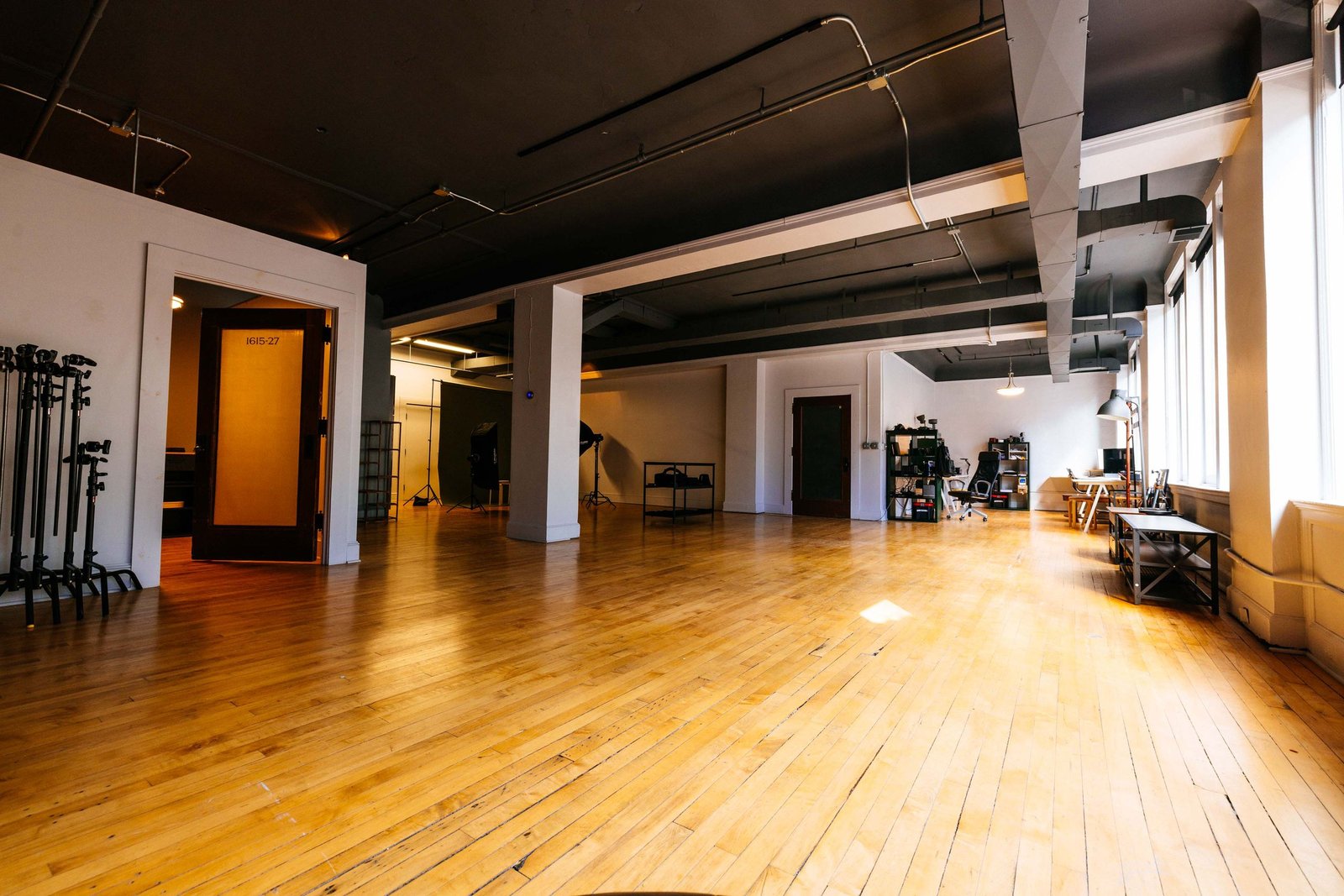 The stage floor at Library St. Studios, hardwood floor, c-stands, and lighting setups under the black ceiling